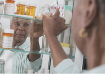 Older woman grabbing medicine from a medicine cabinet