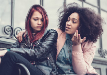 Image of two young girls. One looking sad and the other comforting her 