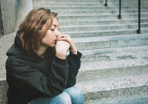 Young girl dressed in a black sweater with a sad expression on her face.
