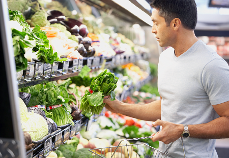 A man holds some spinach as he contemplates what to buy in the produce section