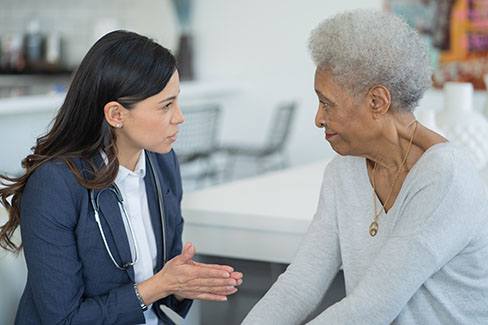 Image of a nurse doing a bedside consultation with a patient