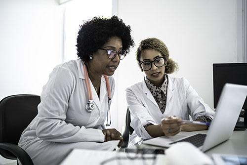 Two medical women working along side each other at a computer
