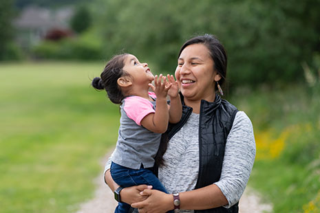 Native American woman smiling and holding a happy toddler