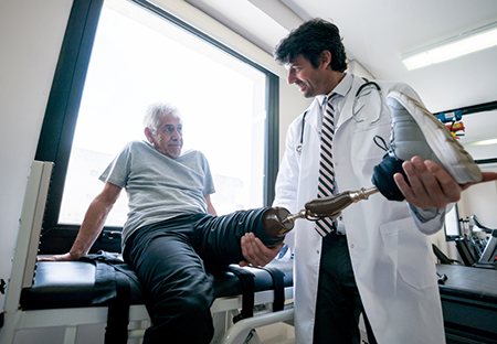A doctor holding the prosthetic leg of an elderly man