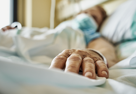 A Covid patient's hand outstretched on a hospital bed