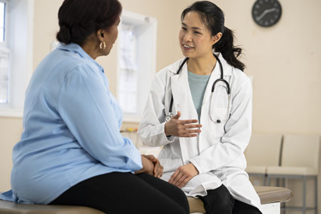 A black woman patient talking to a female medical person