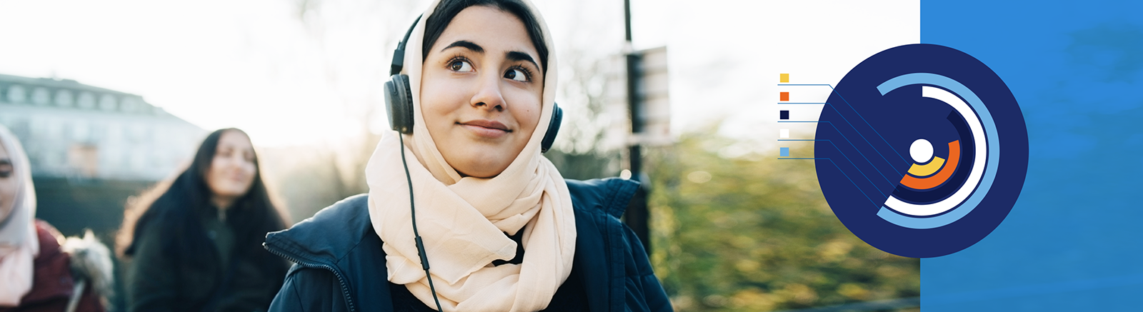A Middle Eastern woman wearing a head scarf and headphones smiling
