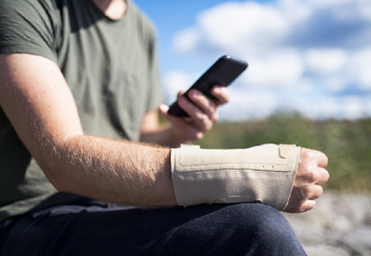 Close up of a seated man's injured wrist in a cast