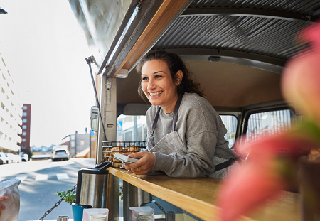 Smiling food truck attendant leans on the counter in front of her