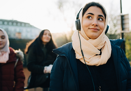 A young woman wearing a hijab and listening to music