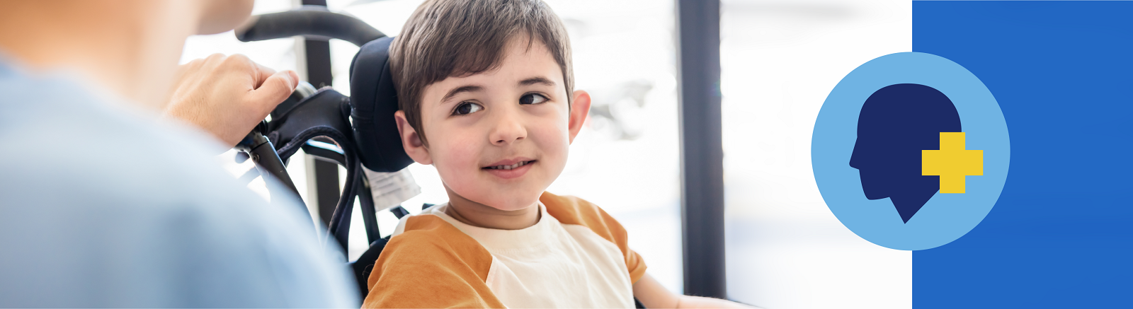 Smiling boy in wheelchair next to graphic of human head with plus symbol next to it