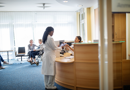 A doctor converses with the receptionist at front reception
