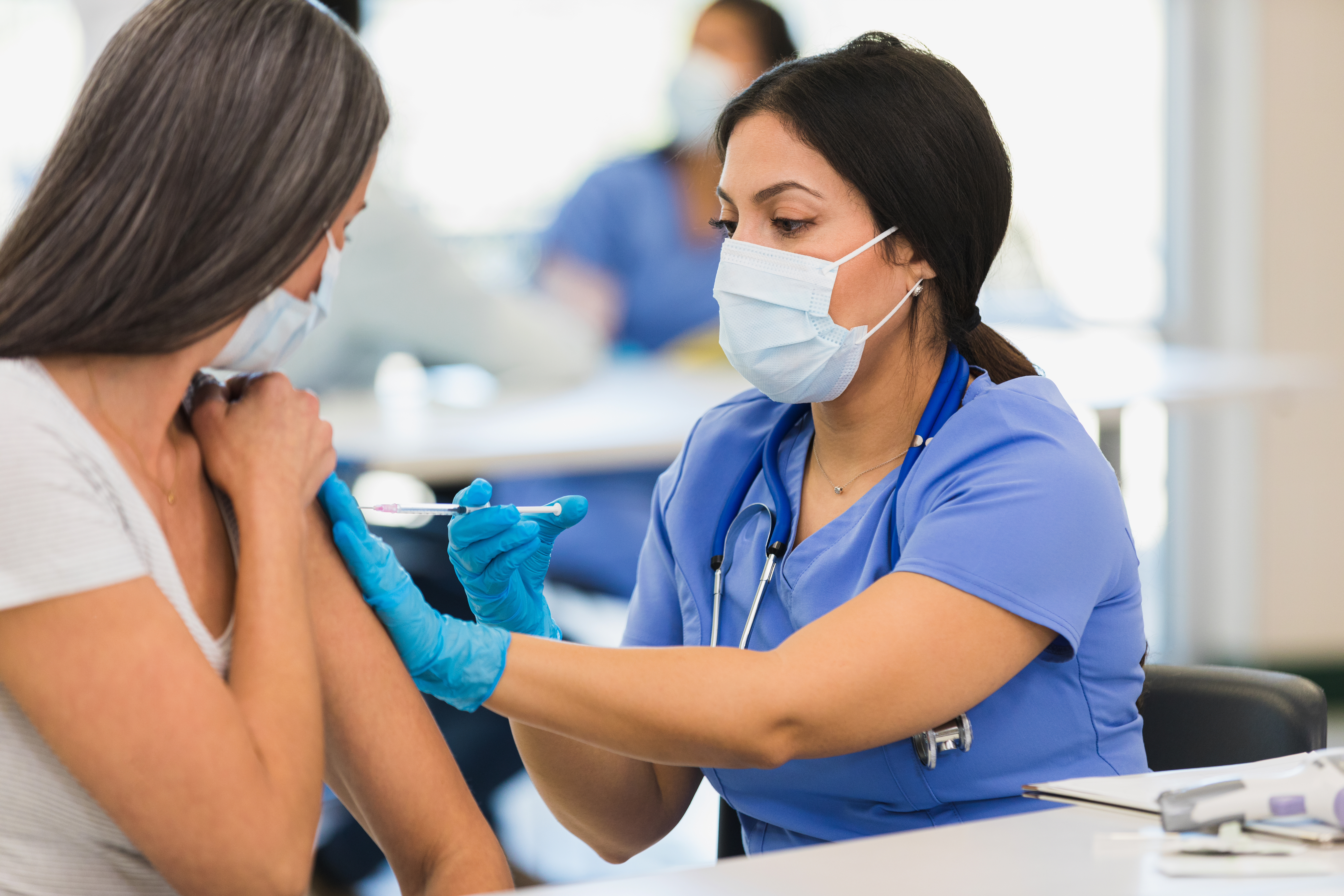 Photo of masked nurse giving shot to patient 