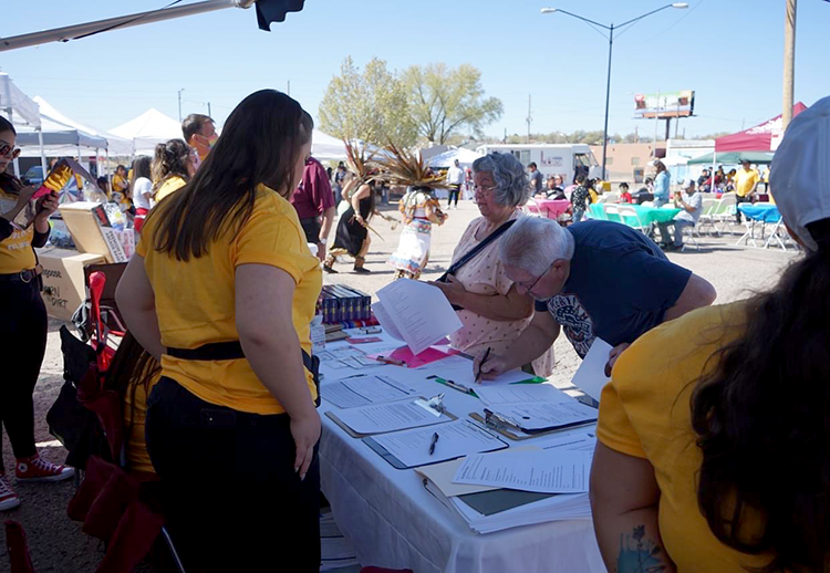 An elderly couple at an event booth signing up for something
